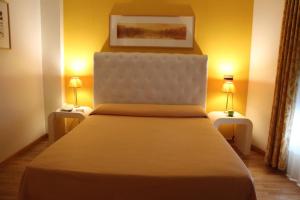 里瓦德奥博萨酒店的一间卧室配有一张大床,桌子上放着两盏灯