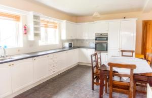 TullaghanDuncarbury Heights - 4 Bedroom Detached House的厨房配有白色橱柜和桌椅