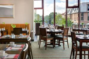 奥格斯堡Rugs Hotel Augsburg City的餐厅设有桌椅和大窗户。