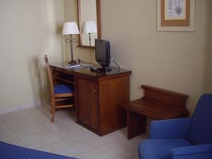 洛斯帕拉西奥西维利亚夫兰卡马诺洛梅奥酒店 的客房设有一张桌子、一台电视和一张蓝色椅子