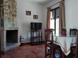 埃尔博斯克卡萨多明加旅馆的客厅配有桌子、电视和壁炉