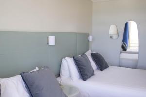格拉德斯通The Gladstone的一间卧室配有白色床和蓝色枕头