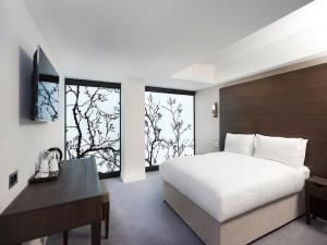 伦敦中央公园酒店的卧室配有白色的床、书桌和窗户。