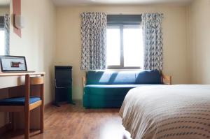 普埃布拉-德阿里冯德Hotel Aragón的一间卧室配有一张床,窗户配有蓝色的沙发