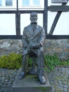 AssinghausenGasthof Kettler的坐在长凳上的男人的雕像