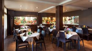 普图伊Hotel Pomaranča的餐厅设有桌椅,墙上挂有绘画作品