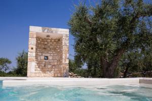 阿尔贝罗贝洛Apulia Relais的一座游泳池,其塔楼毗邻一棵树