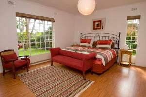 哈拉雷Jacana Gardens的一间卧室配有一张床、一把椅子和窗户。