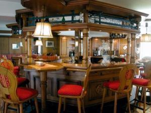 维林根伯格霍夫酒店的餐厅设有酒吧,配有红色的椅子和桌子