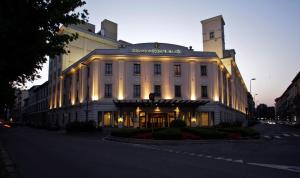 米兰维斯康蒂皇宫豪华酒店的一座白色的大建筑,灯火通明