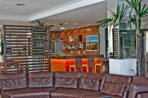 福塔莱萨子午酒店的一间带棕色沙发的客厅和一间酒吧