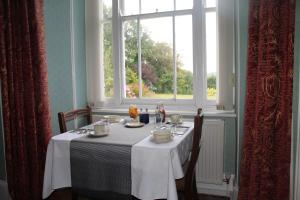 韦德布里奇Trevanger Farm Bed and Breakfast的一张桌子,上面有白色的桌布和窗户
