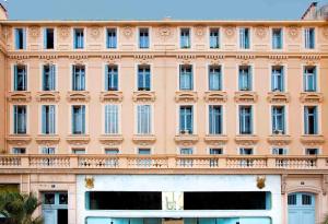 戛纳卢浮宫公寓 - LRA戛纳的一座大型粉红色建筑,设有阳台