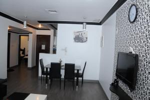 科威特奥林扎塔楼品质公寓的一间带桌椅和电视的用餐室