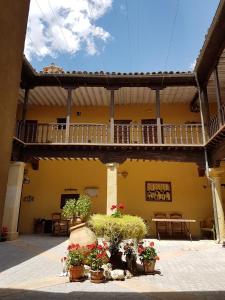 HueteCasa Palacio Conde de Garcinarro的黄色的建筑,种有盆栽植物,设有阳台