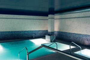 毕尔巴鄂美居加迪纳斯德艾碧亚酒店的一座大楼内带热水浴池的游泳池