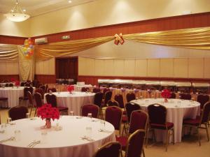 昆达桑京那巴鲁西岭度假酒店的宴会厅配有白色的桌子和椅子,并配以红色的鲜花