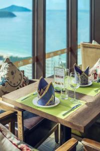 三亚三亚柏瑞精品海景酒店的一张木桌,上面放有盘子和酒杯