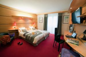 拉布雷斯Hotel & Résidence Les Vallées Labellemontagne的酒店客房设有一张大床和一张书桌。