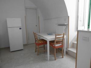 滨海波利尼亚诺La Conchiglia Domus的厨房配有桌椅和冰箱。