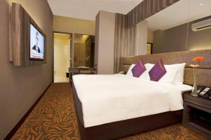 新加坡Aqueen Hotel Paya Lebar的酒店客房配有一张带紫色枕头的大型白色床。