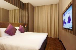 新加坡Aqueen Hotel Paya Lebar的配有一张床和一台平面电视的酒店客房
