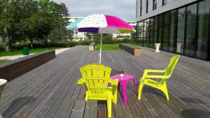 第戎Adonis Dijon Maison Internationale的甲板上配有两把椅子和一张桌子及一把遮阳伞