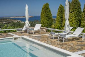 阿吉亚艾里尼帕罗Villas Agia Irini Cove的一个带两把椅子和遮阳伞的游泳池