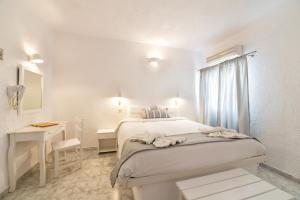梅加洛克里阿尔特弥斯套房酒店的白色卧室配有床和书桌