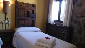 Los Navalucillos瓦尔多拉扎佐乡村民宿的一间卧室配有带毛巾的床和窗户。