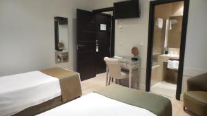 马德里Hotel Moderno Puerta del Sol的酒店客房设有一张床、一张书桌和一间浴室。