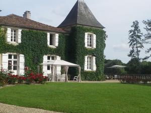 Ruelle-sur-Touvre罗吉斯鲁勒尔住宿加早餐旅馆的常春藤覆盖的房子,配有桌子和椅子