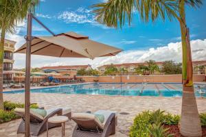 坦帕翡翠绿公寓度假酒店的一个带椅子和遮阳伞的度假游泳池