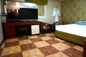 釜山J Motel Gwangalli Busan的一间卧室配有一张床、一台电视和一张书桌