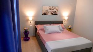 布林迪西Cairoli Exclusive Rooms & Suite的一间小卧室,配有一张粉色和白色床单