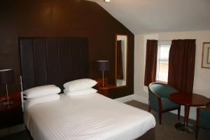 什鲁斯伯里瓦奥尔特斯酒店的卧室配有1张床、1张桌子和1把椅子