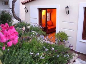 斯卡拉Kekrifalia Hotel的一座花园,在房子前方种有粉红色的花朵