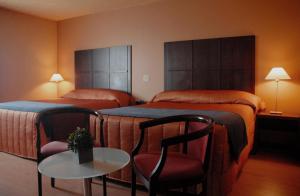 七岛市Hôtel Mingan的酒店客房带两张床和一张桌子以及椅子。