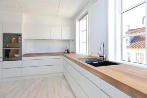 哥本哈根CITY, LUX APARTM - 2 FULL BATHROOMs, 1v的厨房配有白色橱柜和木制台面