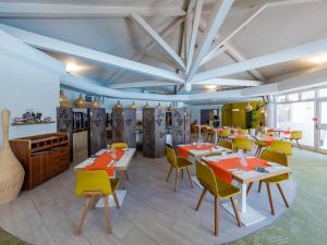 圣拉斐尔加里格爱斯特尔酒店的用餐室配有桌子和黄色椅子