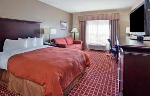 哥伦比亚哥伦比亚卡尔森乡村套房酒店的酒店客房配有一张床、一把椅子和一台电视。