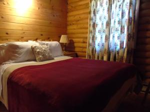 Margaree Forks印第安雪松木屋假日公园的一间卧室配有一张带木墙和窗帘的床