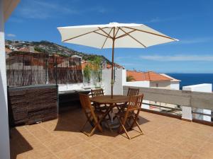 丰沙尔Barreirinha Funcho House的阳台配有桌椅和遮阳伞