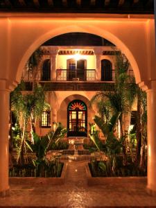 马拉喀什阿尔法希亚阿古达尔酒店的一座建筑中的拱门,庭院里种有植物
