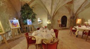 圣阿沃尔德Logis Hotel de Paris的一间带桌椅和绘画的用餐室