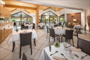 班纳萨克Hôtel-Restaurant Le Calice Du Gevaudan - A75的餐厅设有白色的桌椅和窗户。