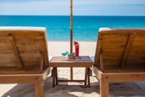 拉迈拉迈椰子海滩度假村的海滩上的两把椅子和一张桌子