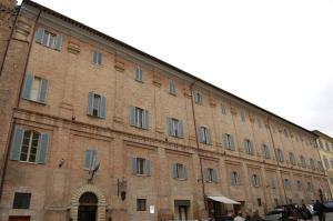 乌尔比诺Guest House Domus Urbino的一座大型砖砌建筑,前面有人