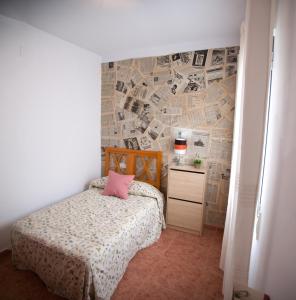 NavahermosaCasa Rural Marchena的一间卧室配有一张床,墙上有报纸