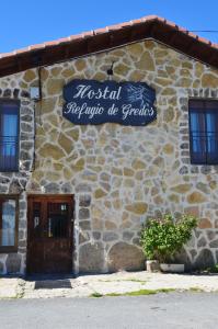 纳瓦雷东达德格雷多斯Hostal Refugio De Gredos的一座石头建筑,旁边标有标志
